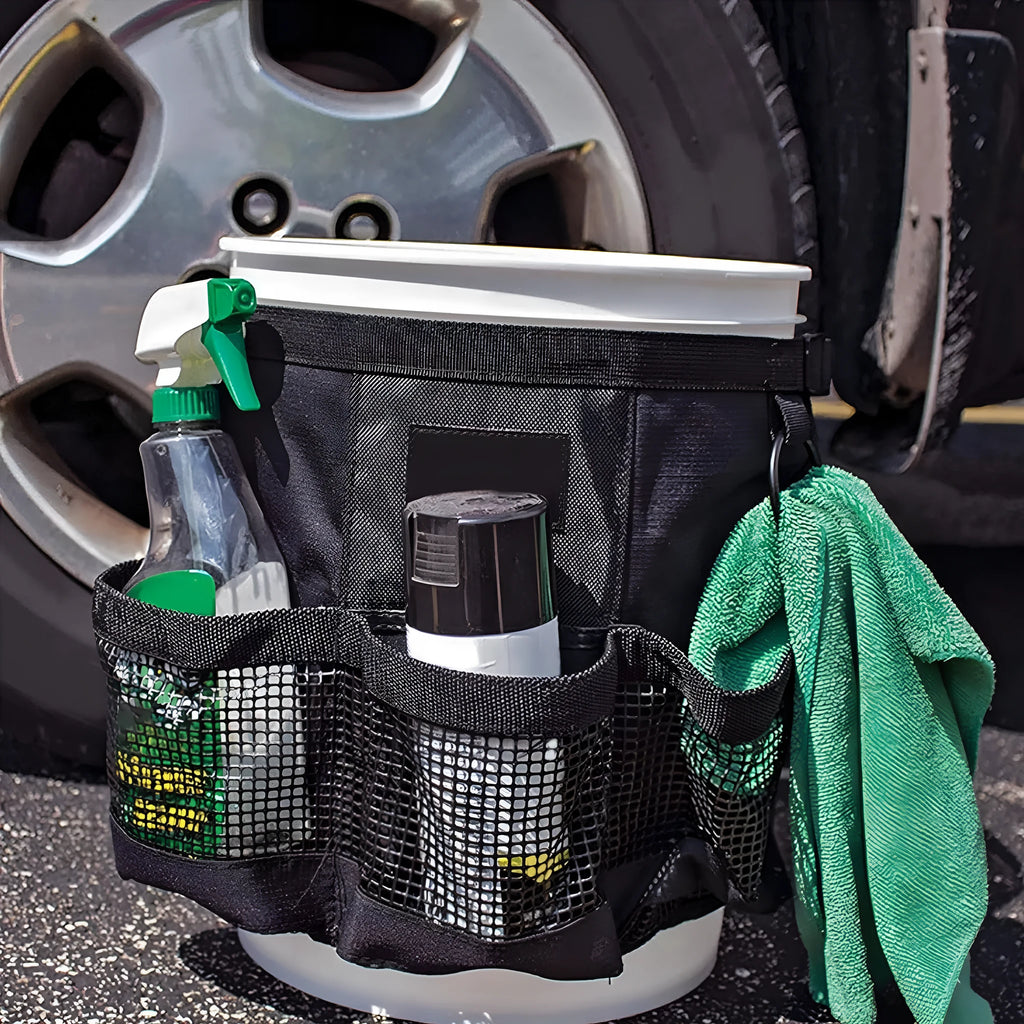 Black cylindrical polyester storage bag hanging on a 5-gallon barrel for outdoor tool organisation.