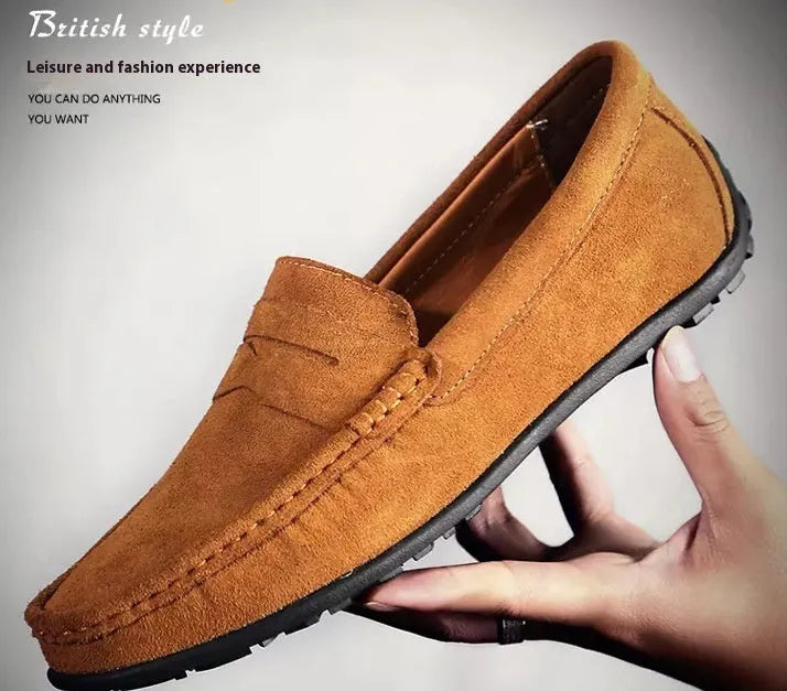 Men's suede slip-on loafers in black on a flat rubber sole, showing round toe and sewing detail.