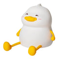 Chubby white rechargeable LED night light with silicone touch top on a wooden desk next to a phone.