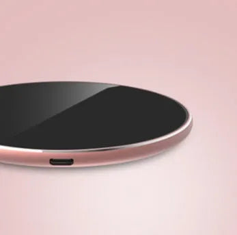 Slim aluminium wireless charging pad in rose gold colour on a wooden surface