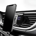 Black car phone holder mounted on vehicle air vent with adjustable clamping arms extended