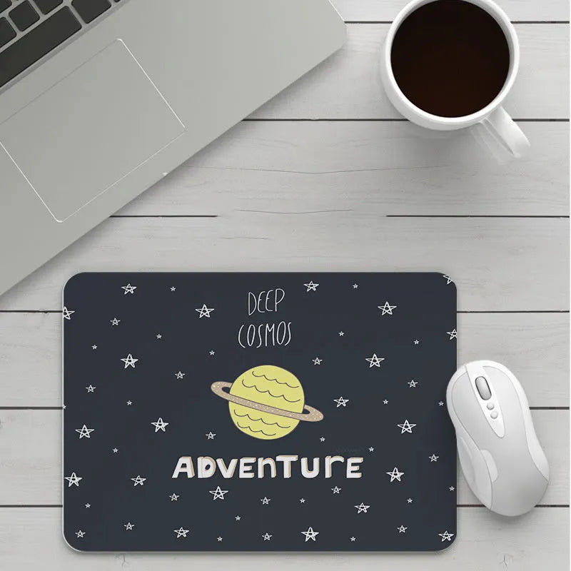 Custom cartoon design on a small black thickened mouse pad with stitching, shown on a desk.