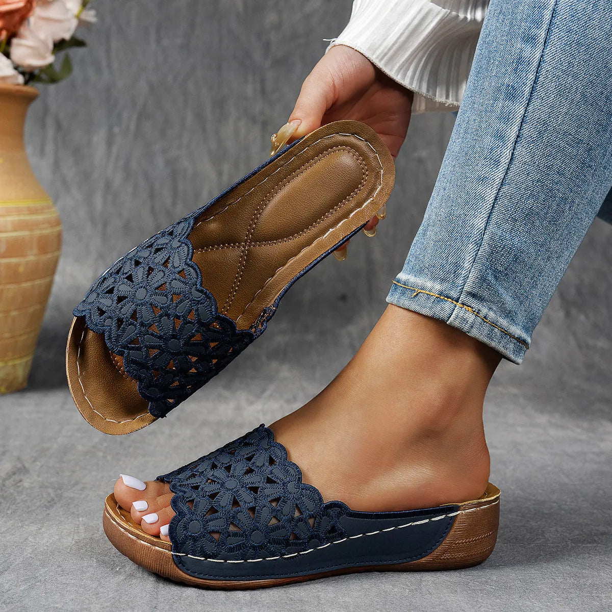 Women's black beach slippers with flower cutout design on the PVC upper and a rubber wedge sole.