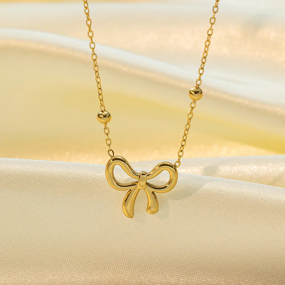 Gold electroplated bow necklace on cross chain with adjustable length