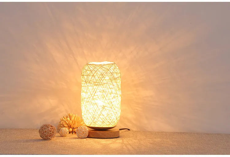 Handmade brown hemp rope spherical desk lamp with a solid wood base on a desk.
