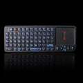 Black wireless laser teaching mini keyboard with touch screen on a desk next to a laptop.