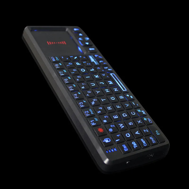 Black wireless laser teaching mini keyboard with touch screen on a desk next to a laptop.