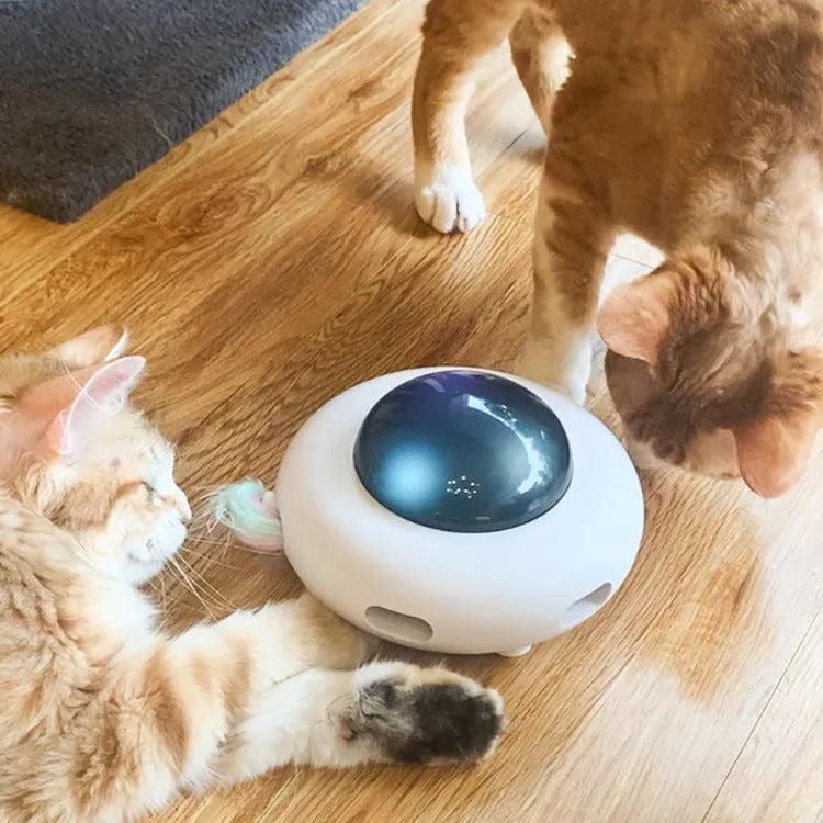 White UFO electric cat turntable toy with feather accessories on floor