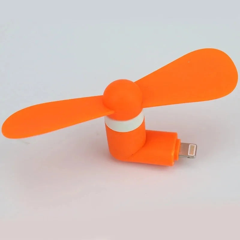 White portable mini fan with plastic blades and rotary switch attached to a mobile phone.