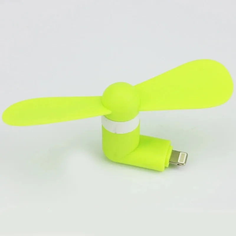 White portable mini fan with plastic blades and rotary switch attached to a mobile phone.