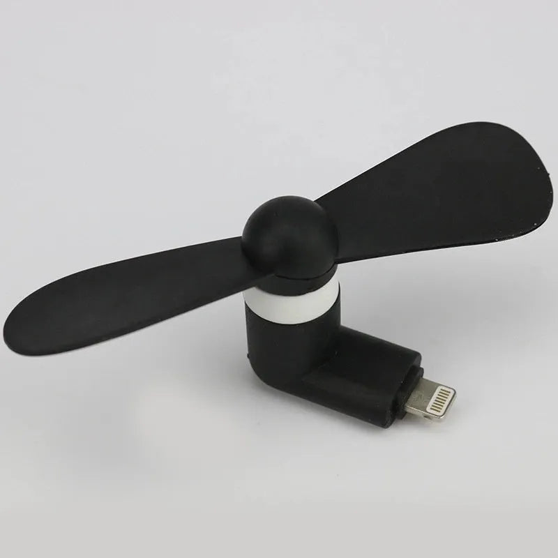 White portable mini fan with plastic blades and rotary switch attached to a mobile phone.