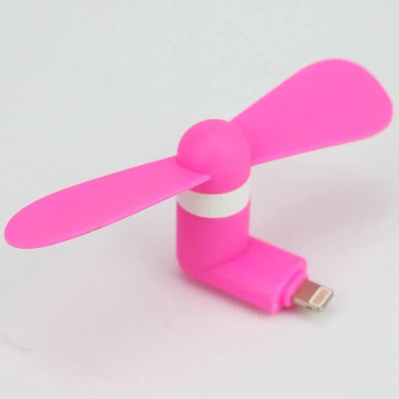 White portable mini fan with plastic blades and rotary switch attached to a mobile phone.
