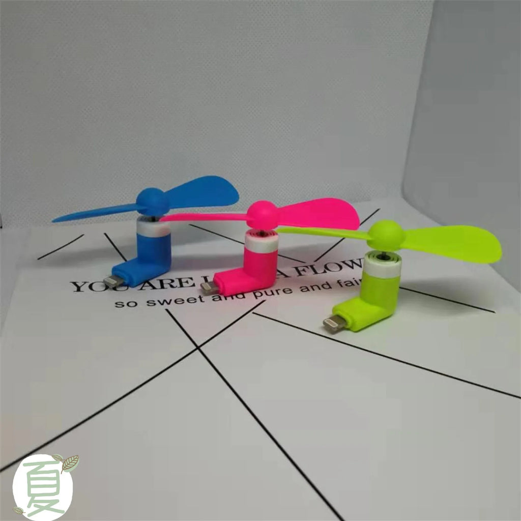 White portable mini fan with plastic blades and rotary switch attached to a mobile phone.