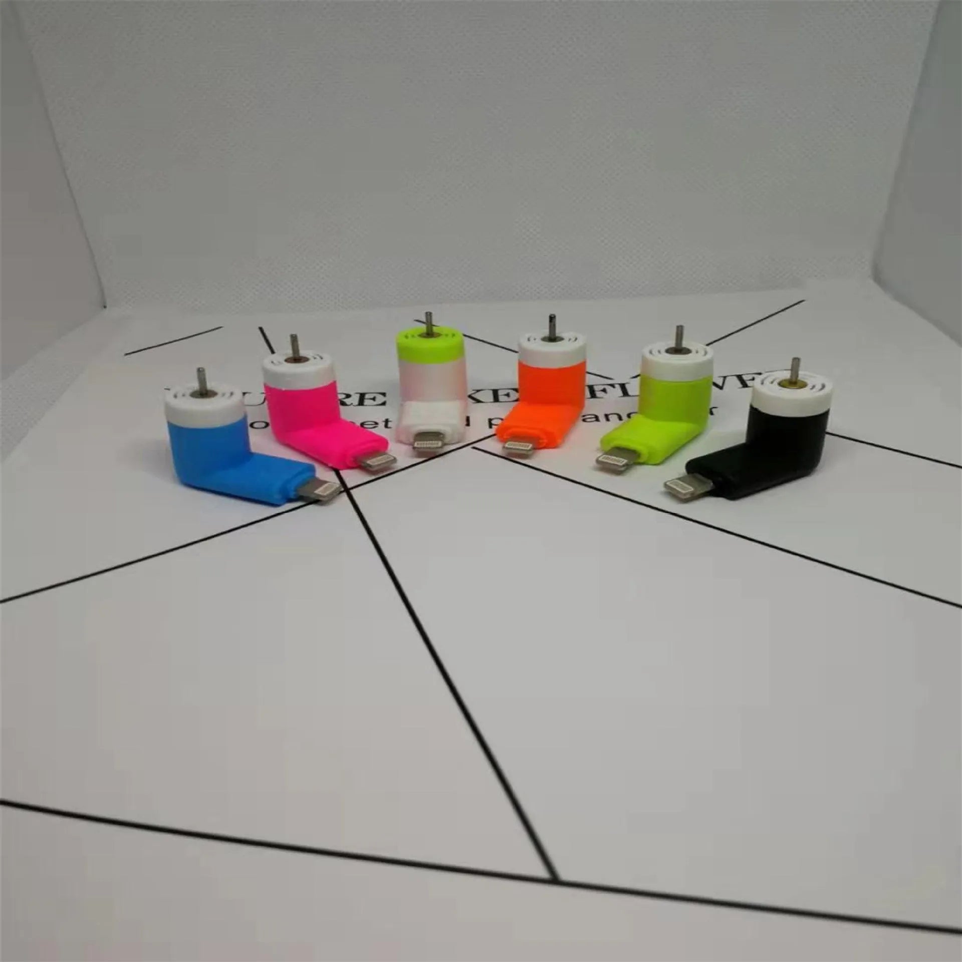 White portable mini fan with plastic blades and rotary switch attached to a mobile phone.