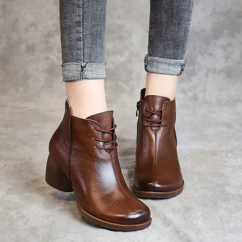 Brown women's leather Martin boots with a thick round heel and round toe on a wooden floor.