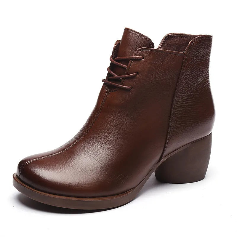 Brown women's leather Martin boots with a thick round heel and round toe on a wooden floor.