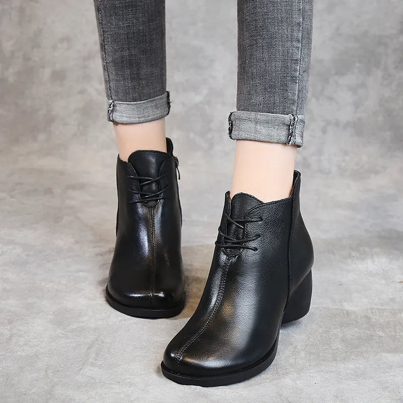 Brown women's leather Martin boots with a thick round heel and round toe on a wooden floor.
