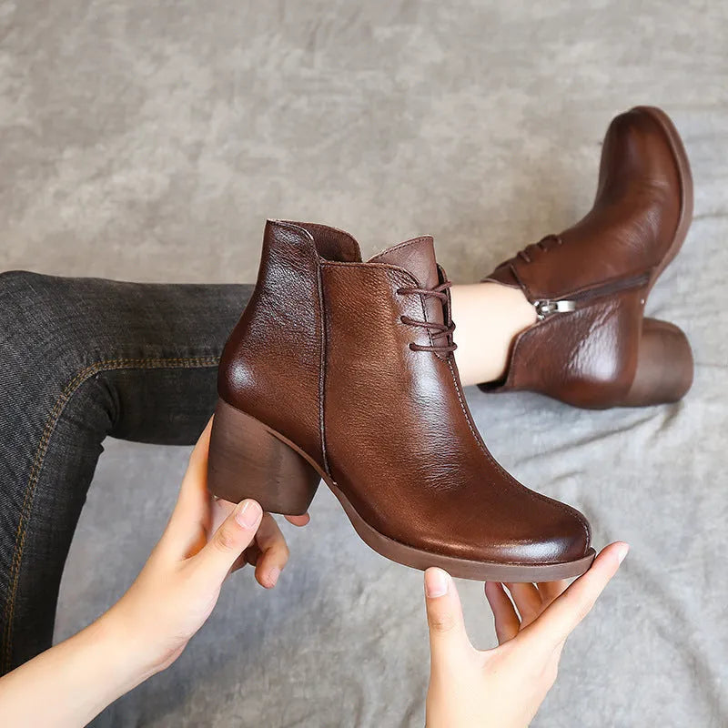 Brown women's leather Martin boots with a thick round heel and round toe on a wooden floor.