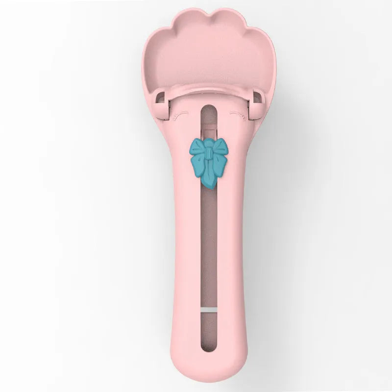 Green and pink pet food scooper spoon with squeezer handle and extruded feeder tip for dispensing treats.