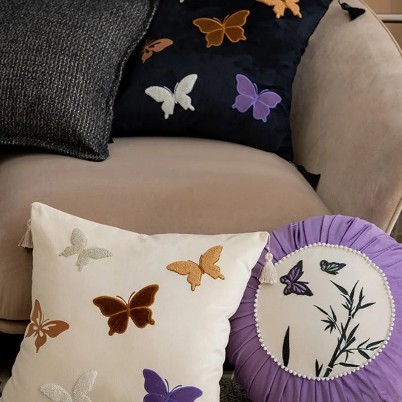 Square beige cushion with detailed black butterfly embroidery in a Chinese style pattern.