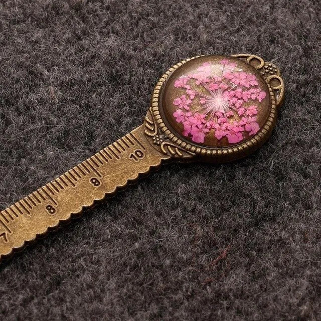 Handmade dried flower bookmark with lace flowers, daffodils, and clover, measuring 12cm long, on a book.