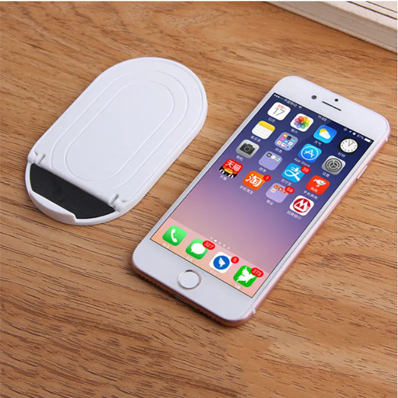 Plastic lazy bracket mobile phone stand in multiple colours on a desk