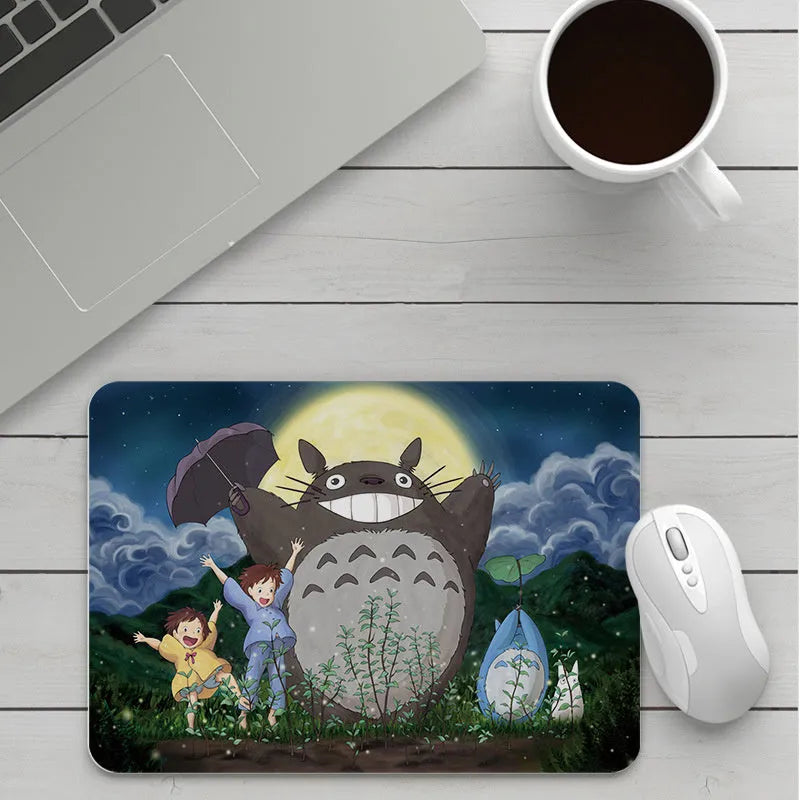 Custom cartoon design on a small black thickened mouse pad with stitching, shown on a desk.