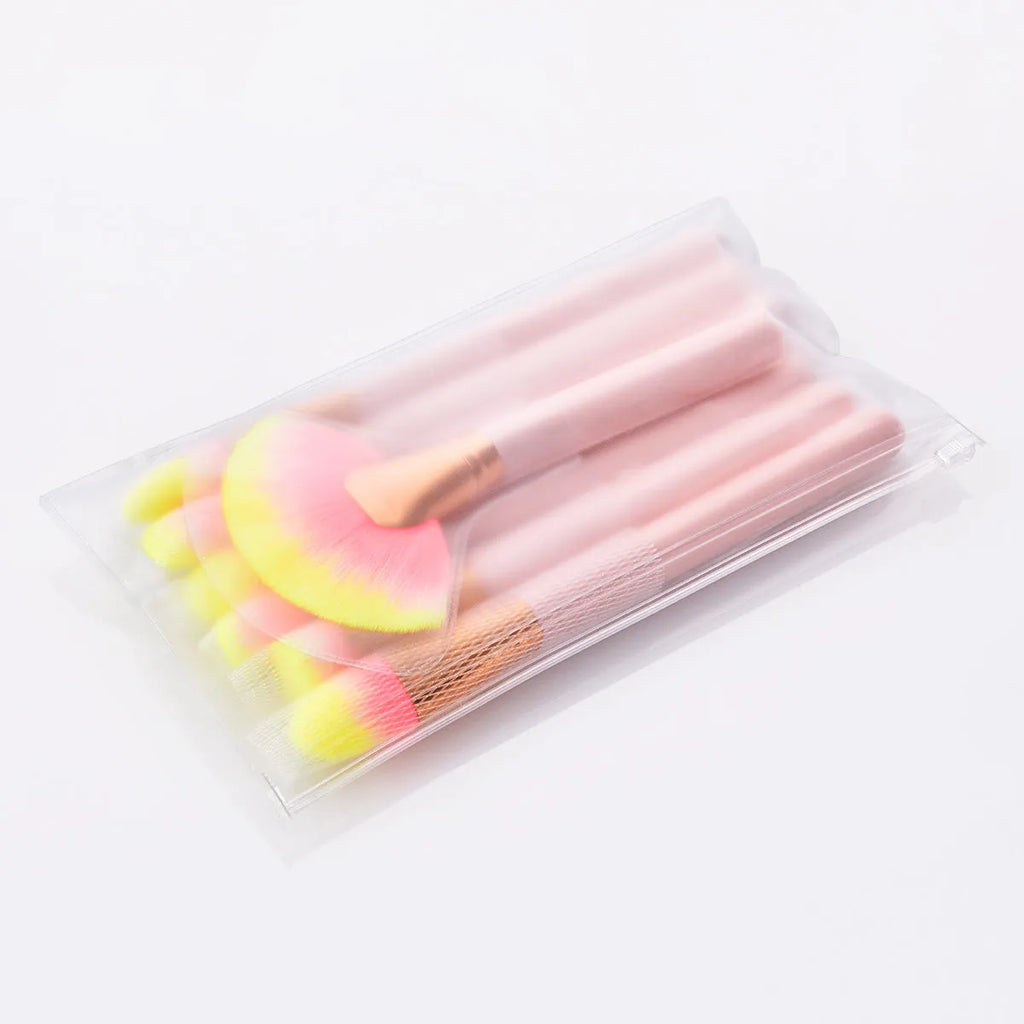 Pink 10-piece makeup brush set with nylon wool bristles and wooden handles laid out on a flat surface