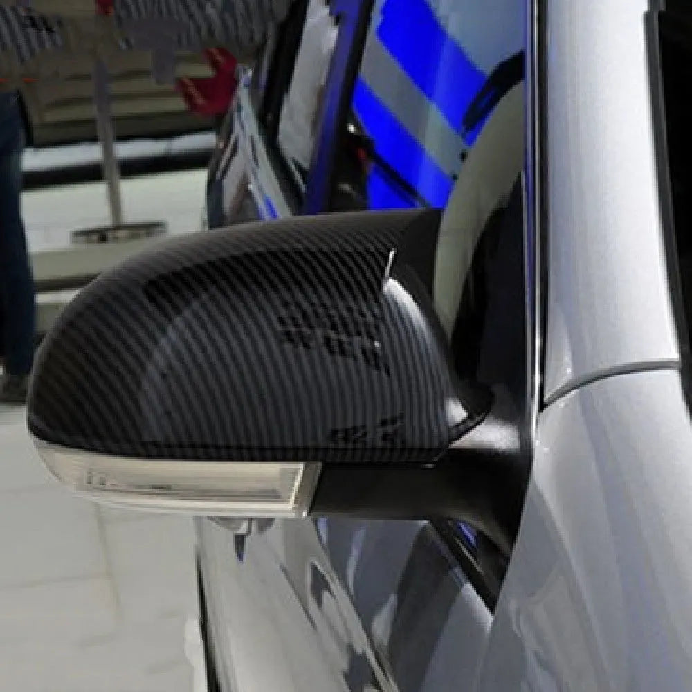 Pair of plastic Volkswagen Sagitar mirror housings in bright black and carbon fibre style finishes.