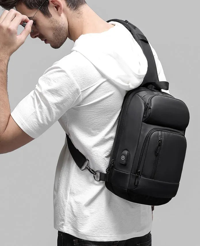 Black PVC outdoor shoulder bag showing computer pocket, air cushion strap, and organisational compartments