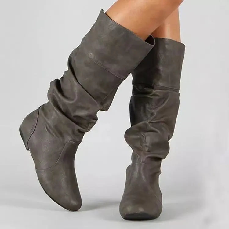 Women's black flat slip-on boots with round toe and high ankle shaft.