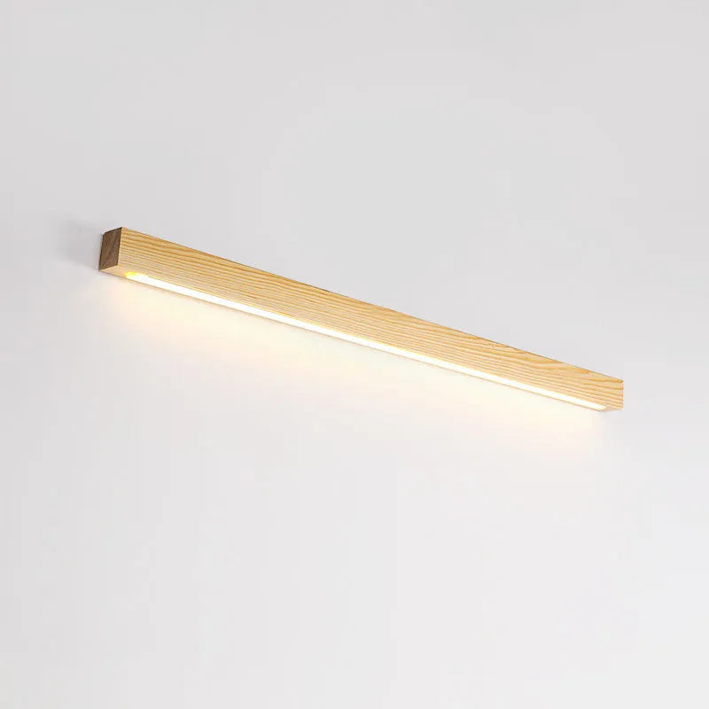 Slim walnut-coloured wooden strip LED wall lamp in three length options on a white wall.
