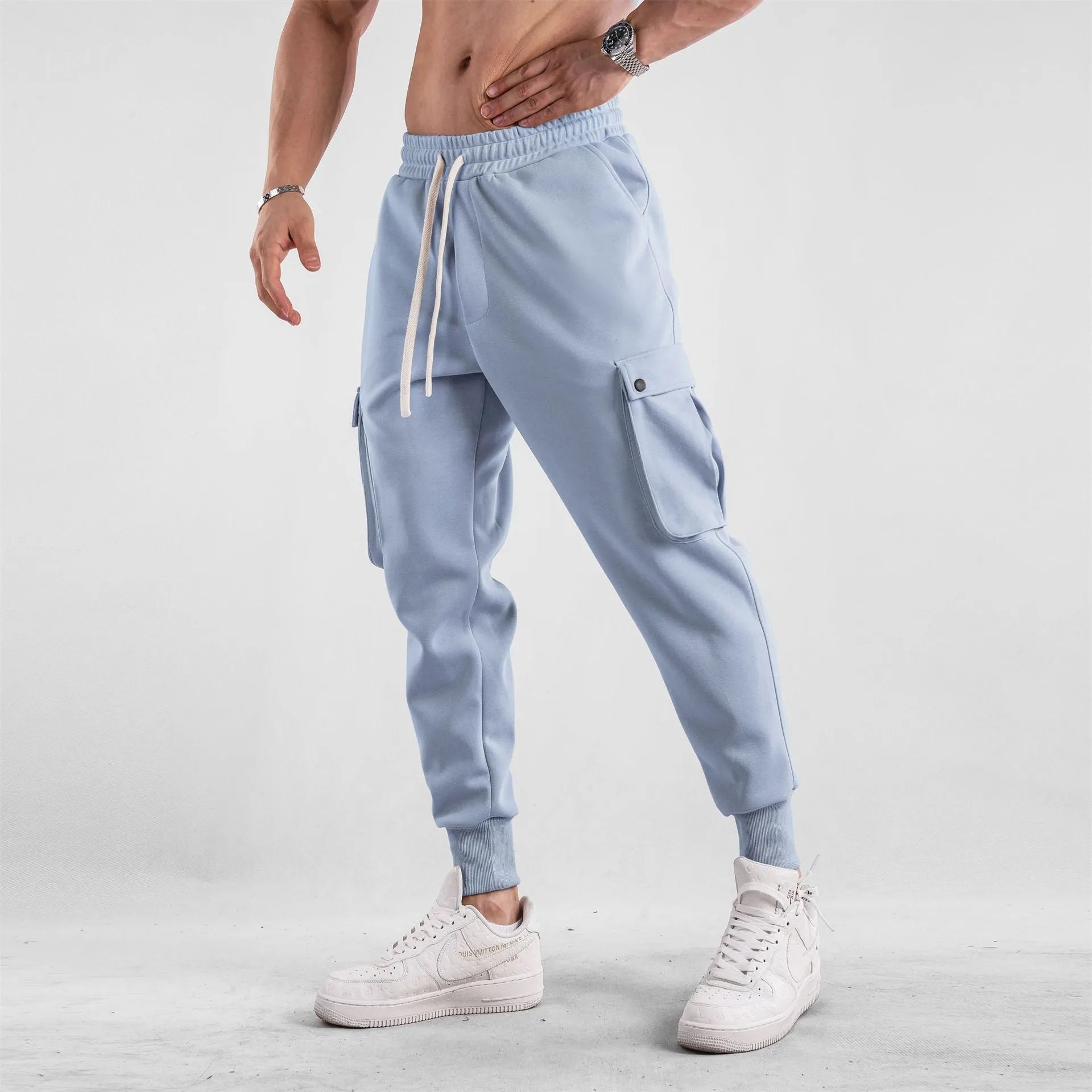 Men's loose fit cotton trousers with ankle-tied cuffs and multiple pockets in a light grey colour.