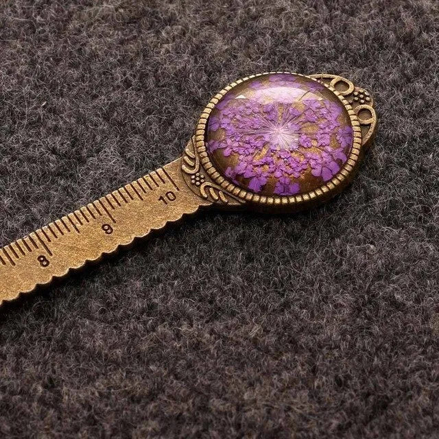Handmade dried flower bookmark with lace flowers, daffodils, and clover, measuring 12cm long, on a book.