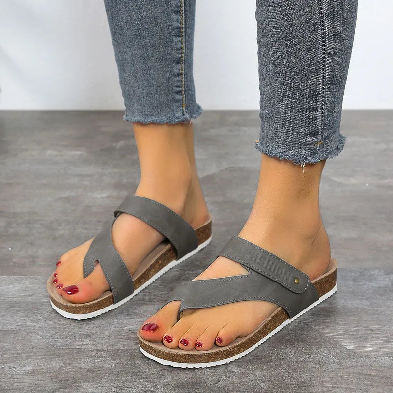 Thick-soled blue flip-flops with flat toe ring design on beach background