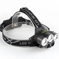 Black head-mounted LED camping torch with adjustable strap and long-range beam shown in outdoor setting.