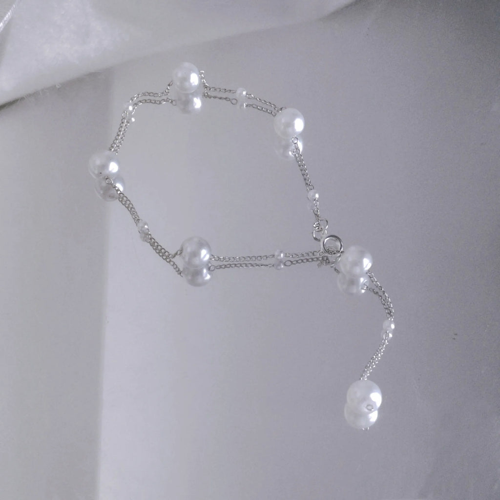 Gold starry pearl choker necklace on a white surface showing imitation pearl chain