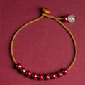 Close-up of a hand-woven geometric bracelet made from cinnabar and Hetian jade stones.