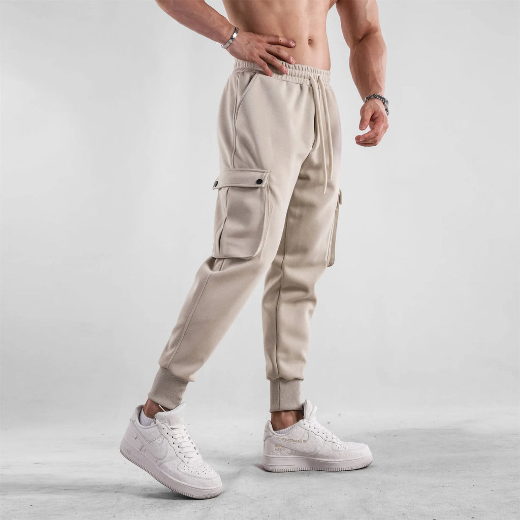 Men's loose fit cotton trousers with ankle-tied cuffs and multiple pockets in a light grey colour.