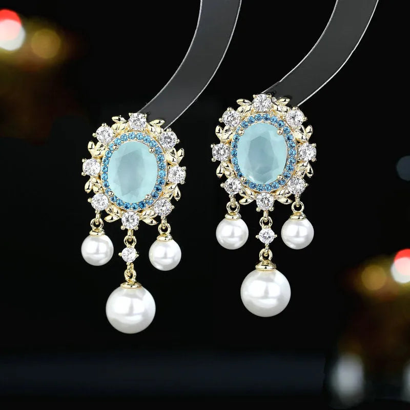 Oval-shaped geometric drop earring with a pearl tassel and inlaid zircon crystals in light purple.