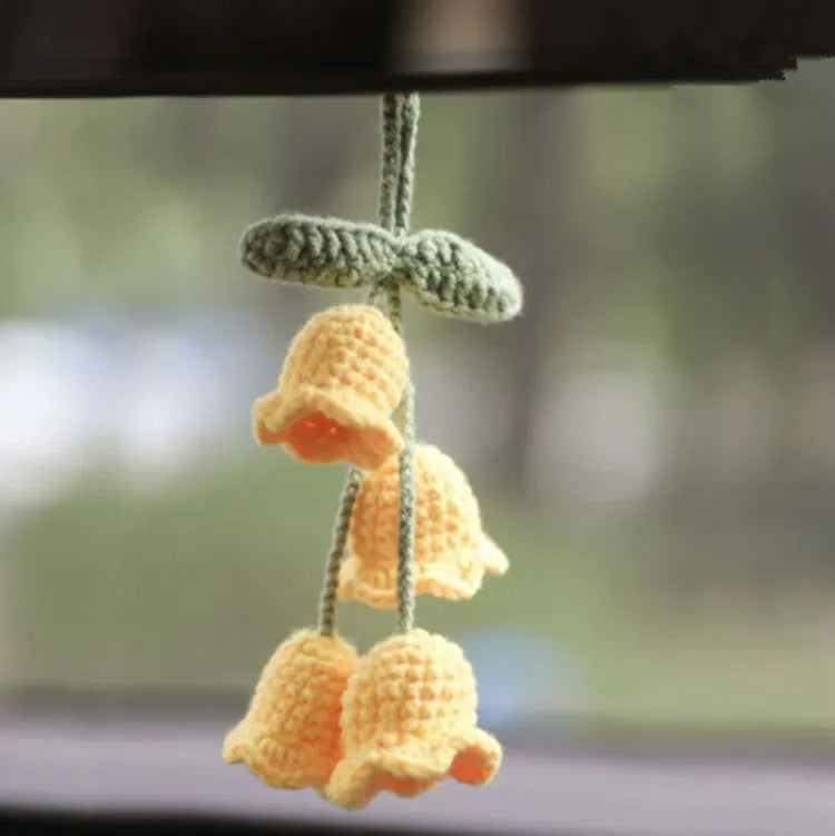 Green and white crochet wool car plant decoration with hanging rope on car dashboard