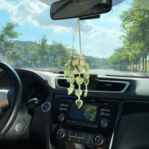 Green and white crochet wool car plant decoration with hanging rope on car dashboard