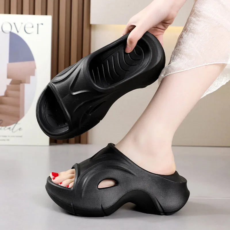 Women's white thick-soled EVA slippers with rounded toe on a sandy beach.