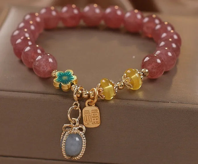 Red women's beaded bracelet made with natural strawberry quartz stones, alloy spacers, and rhinestone accents.