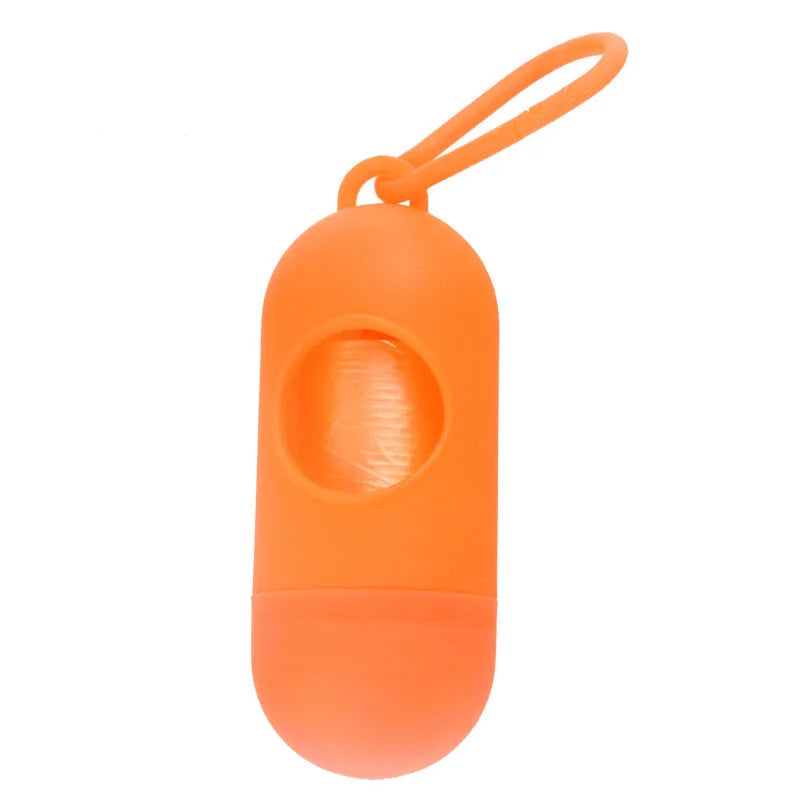 Compact black dog poop bag holder with hook and Velcro strap, shown attached to a pair of trousers.