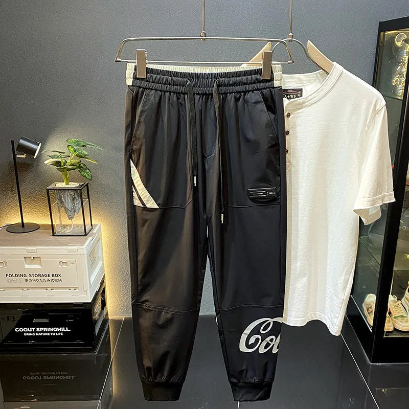 Men's solid black cotton trousers with elasticated ankle bands, shown in a casual style.