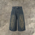 Men's black denim shorts with flame embroidery patches on the legs, showing a cropped, straight-leg cut.
