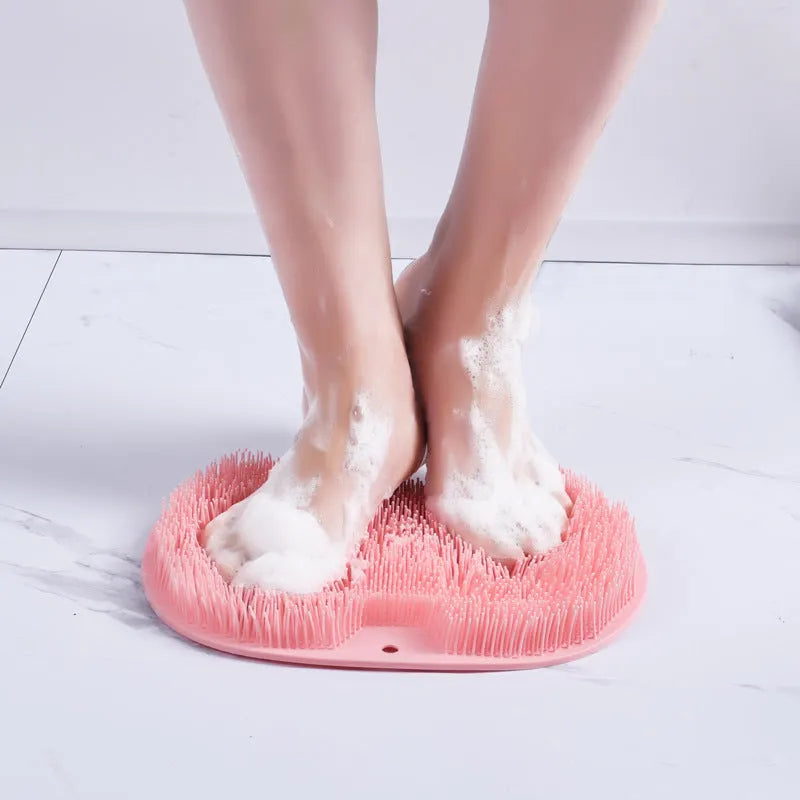 Orange silicone bristle bath brush with suction cup base on a bathroom floor.