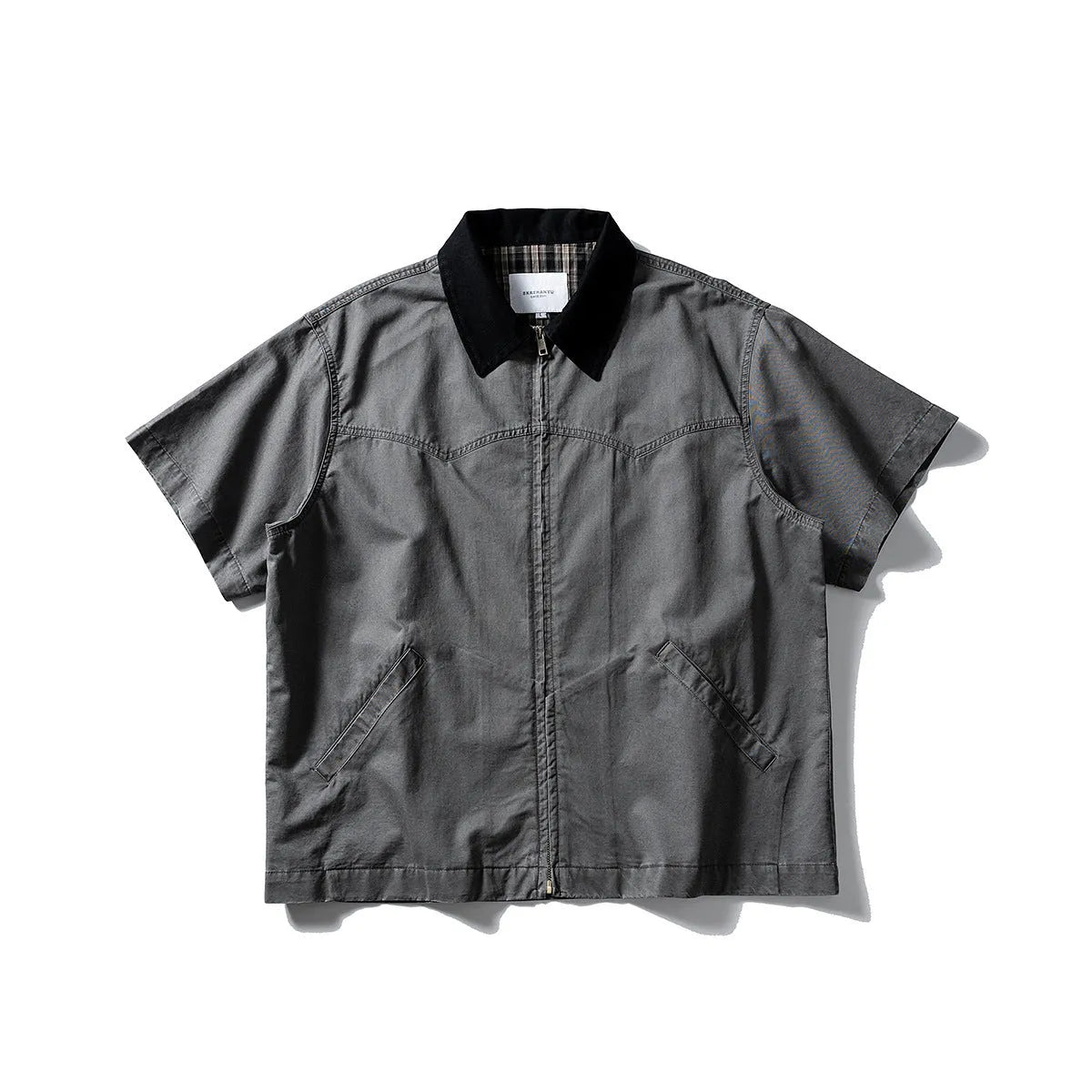 Washed khaki loose-fit cotton overalls shirt with short sleeves on a hanger.