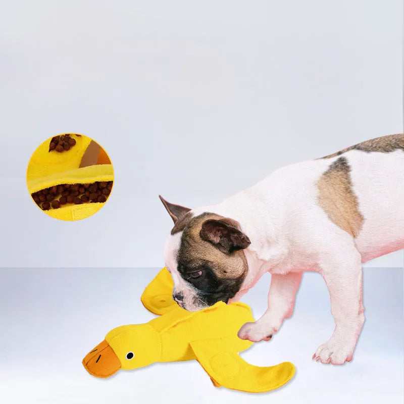 Yellow plush teddy bear dog toy with a small duck doll attached, showing food dispensing holes.